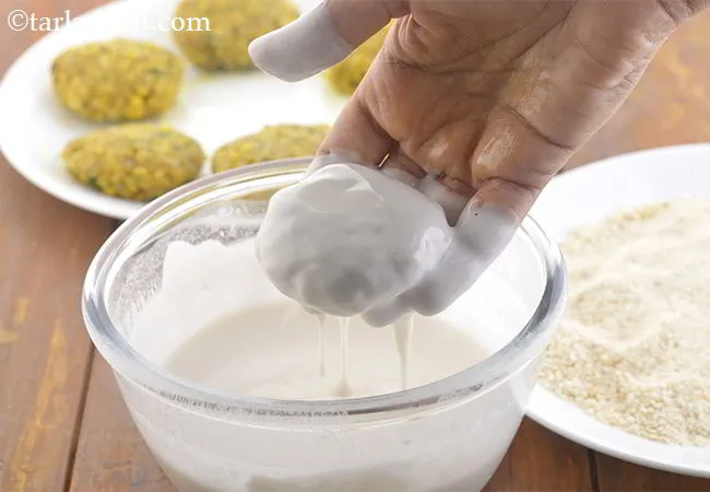 Step 22 – Keep the maida mixture and the breadcrumbs ready side by side. Dip one kebab in …