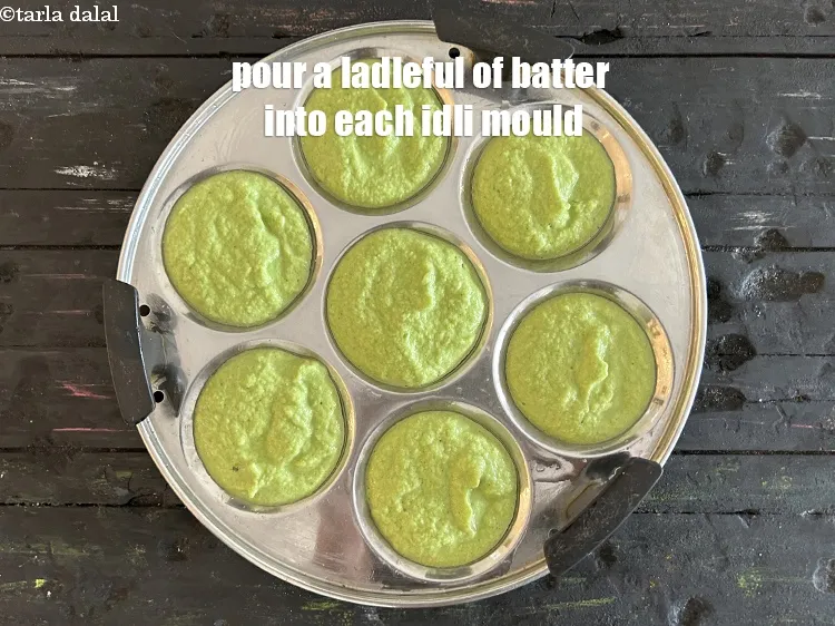 Step 24 – <meta charset="UTF-8" />Pour a ladleful of batter into each greased idli mould.&nbsp;