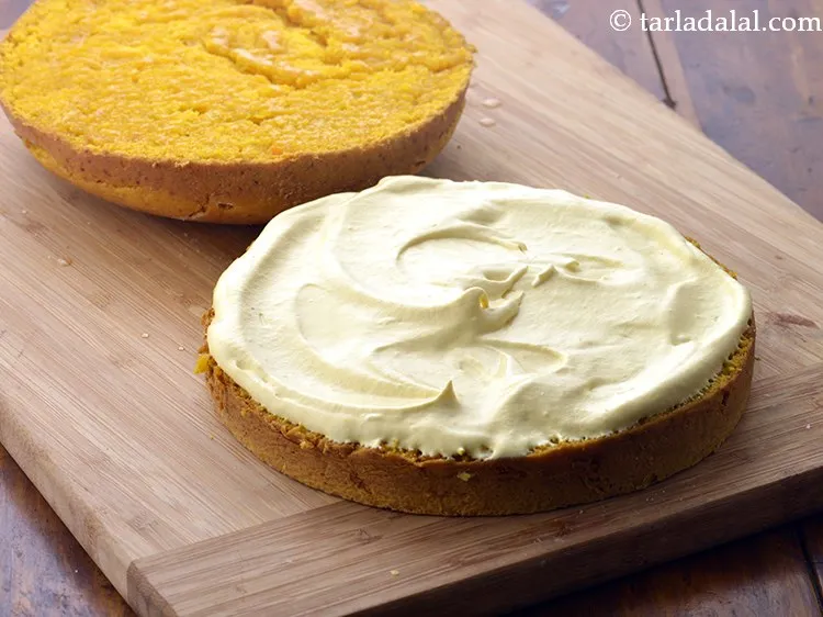 स्टेप 30 – केक के निचले हिस्से पर &frac12; कप तैयार मैंगो आइसिंग …