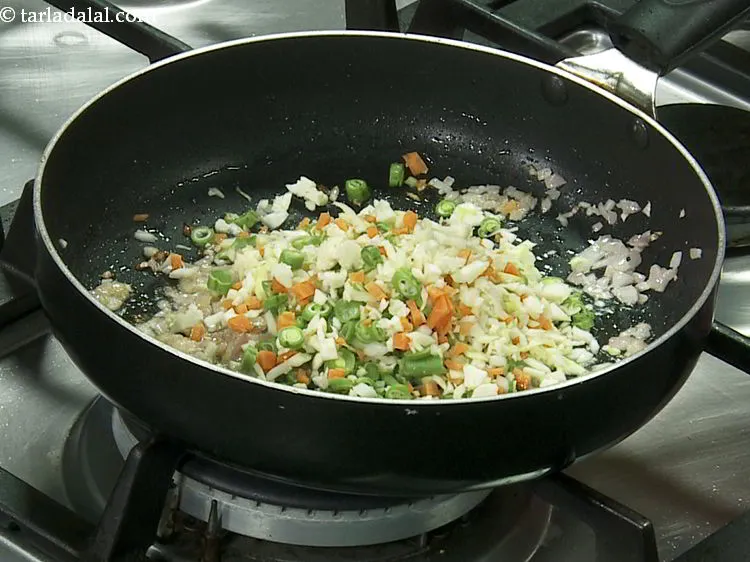 स्टेप 6 – मिली-जुली सब्जियाँ डालें। हमने पत्तागोभी , फूलगोभी और फण्सी का …