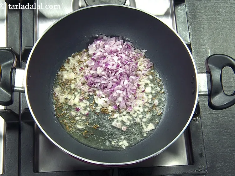 Step 15 – When the seeds crackle, add 1/2 cup&nbsp;finely&nbsp;<a href="https://www.tarladalal.com/glossary-chopped-onions-722i">chopped onions</a>.
