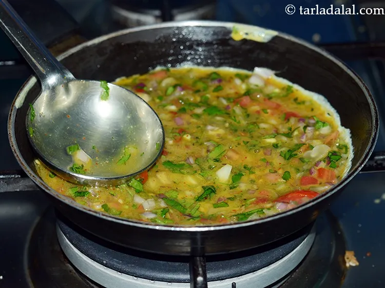 Step 13 – Pour a ladleful of the mixture on it and tilt the tava slightly to distribute …