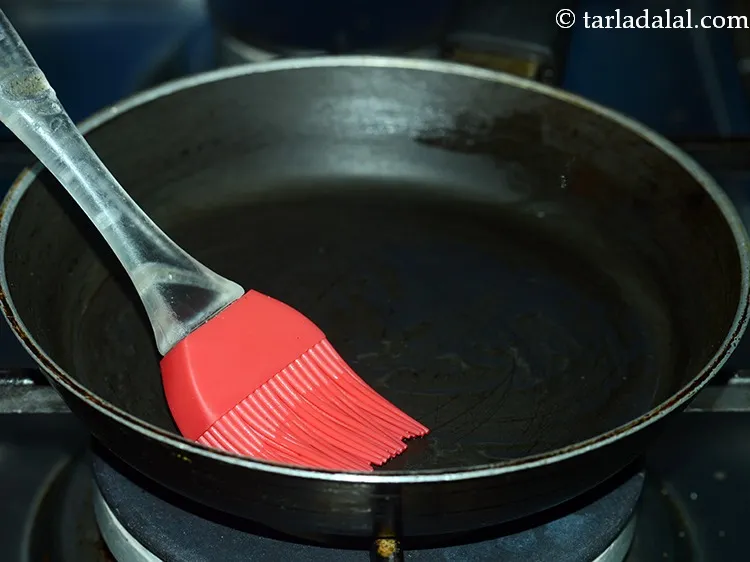 Step 12 – To cook Indian masala omelette, heat a non-stick tava( griddle), grease it with &frac14; tsp …