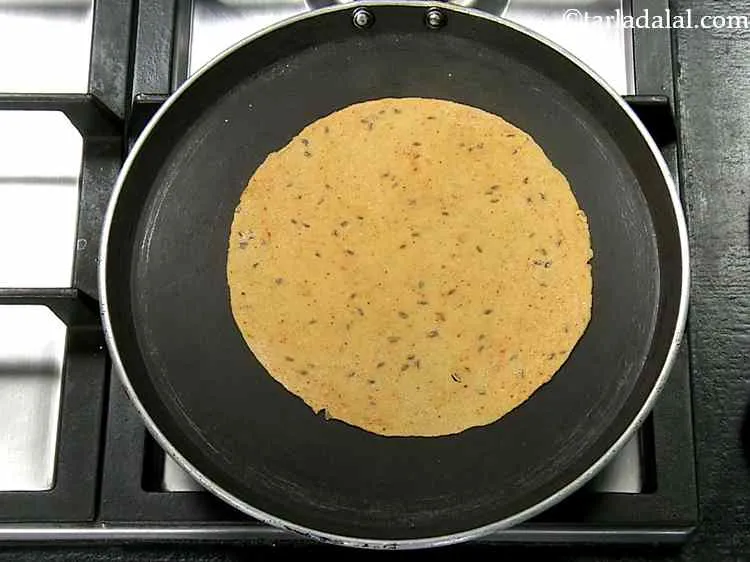 Step 13 – Heat a non-stick tava (griddle) and place the rolled dough onto it.