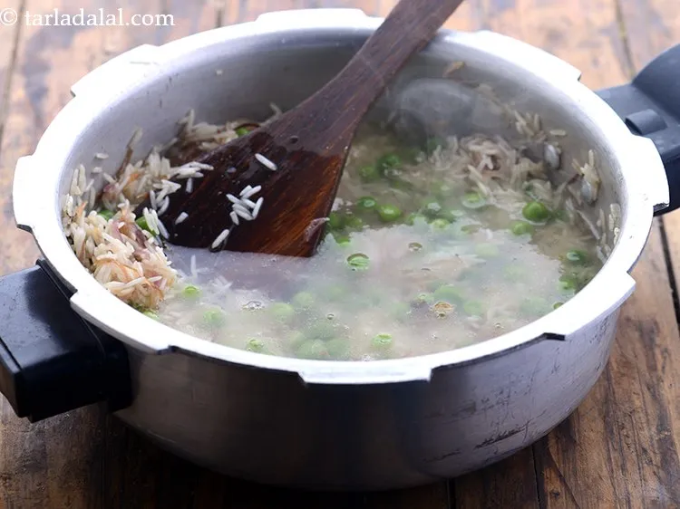 स्टेप 16 – नमक और १ १/२ कप गरम पानी डालें। चावल पकाने …