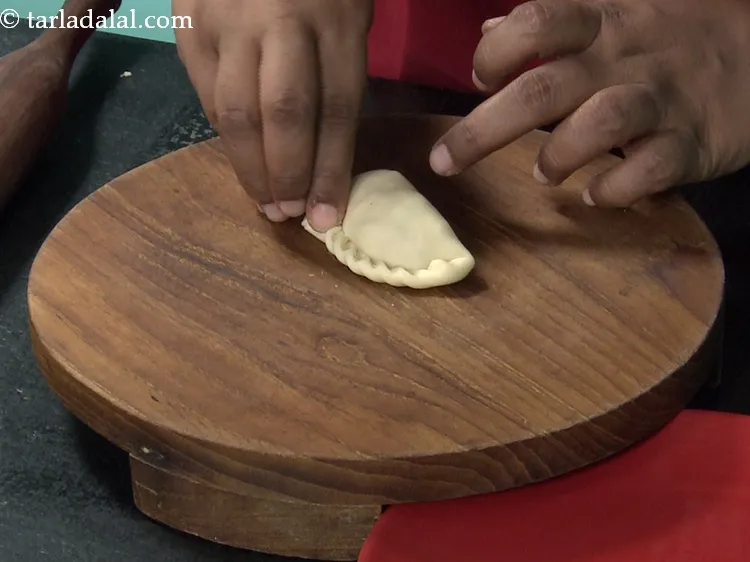 Step 43 – Twist the sides of the karanji inwards to form pleats. Be careful to twist at …