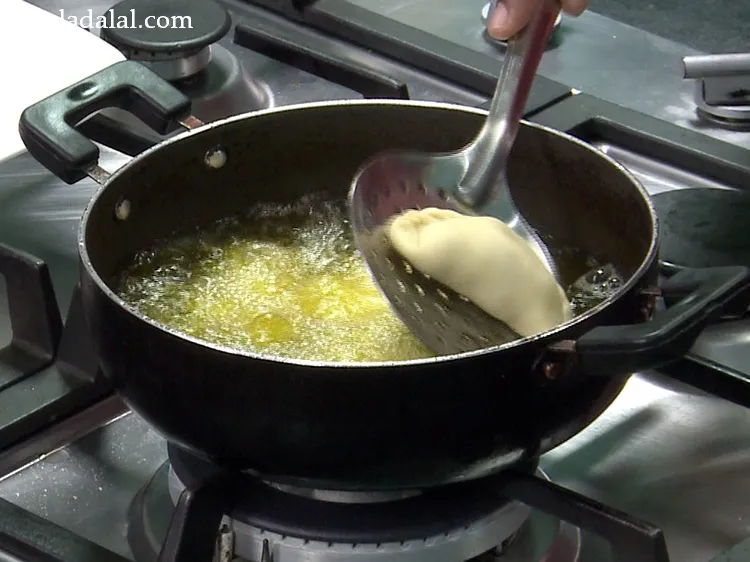Step 46 – Add a few karanjis at a time in hot ghee.