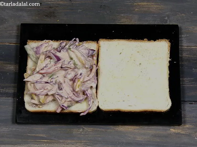 स्टेप 12 – मक्खन लगी हुई एक ब्रेड स्लाइस के ऊपर समान रूप …