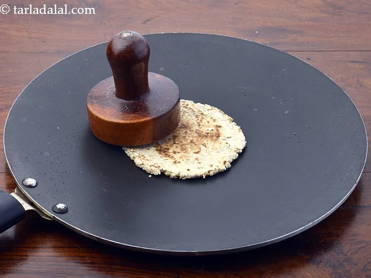 Step 26 – Continue cooking the bhakri on a slow flame, while pressing with a folded muslin cloth …