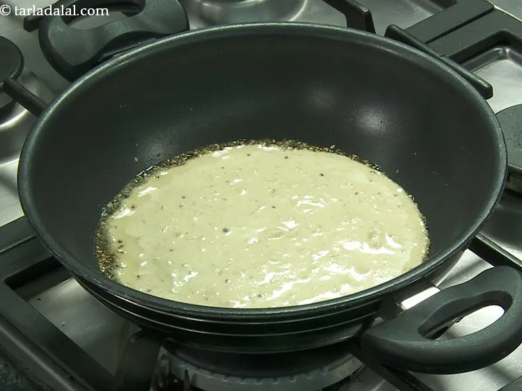 Step 28 – Pour half the <strong>handvo</strong> batter evenly over the tempering to make a thick layer.