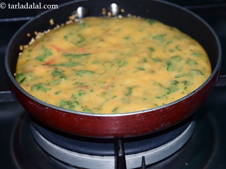 स्टेप 19 – एक ढक्कन ढक कर <strong>गुजराती स्टाइल मिक्स वेजिटेबल हांडवो</strong> को …