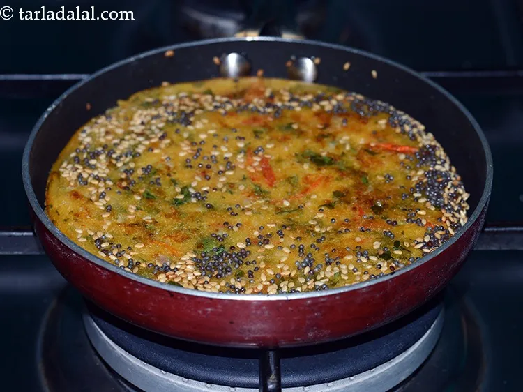 स्टेप 20 – फिर से दिलकश <strong>वेजिटेबल हांडवो</strong> को ढक्कन ढक कर, मध्यम …