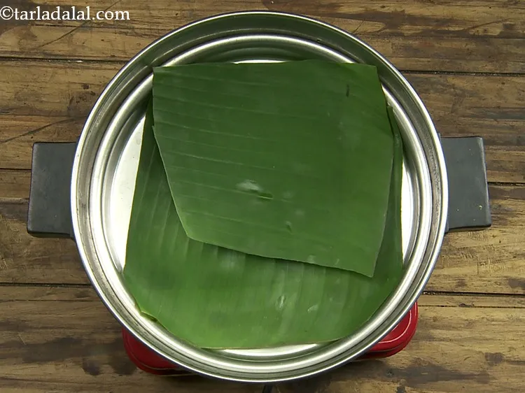 Step 23 – <p>Heat water in the steamer. Meanwhile, place a banana leaf on the steamer plate.</p>