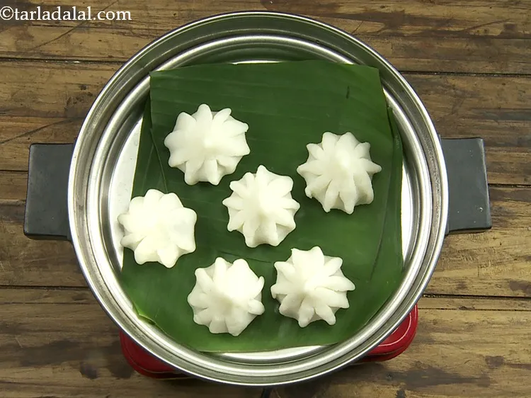 Step 24 – <p>Place the steamer plate inside the steamer and put 6 <strong>modaks</strong> on the banana leaf.</p>