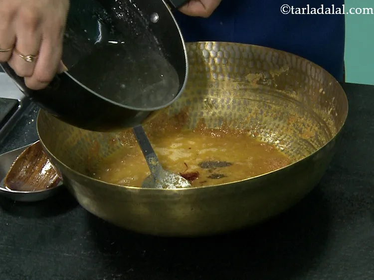 Step 27 – Also, add the prepared sugar syrup to the cooled besan mixture.