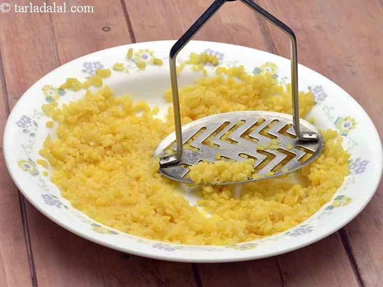 Step 17 – Transfer the cooked dal into a plate and mash it lightly using a potato masher.