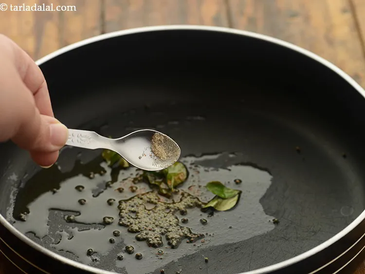 Step 20 – When the mustard seeds crackle,&nbsp; add asafoetida.
