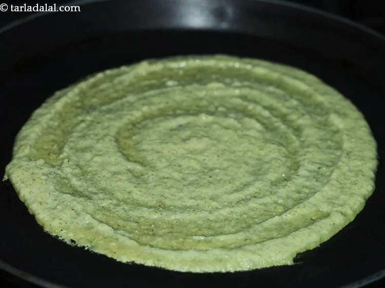 Step 35 – Pour a ladleful of the batter on the tava and spread it evenly in a …