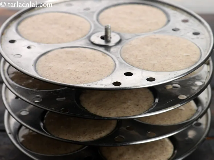 Step 50 – Pour spoonfuls of the batter into greased idli moulds.