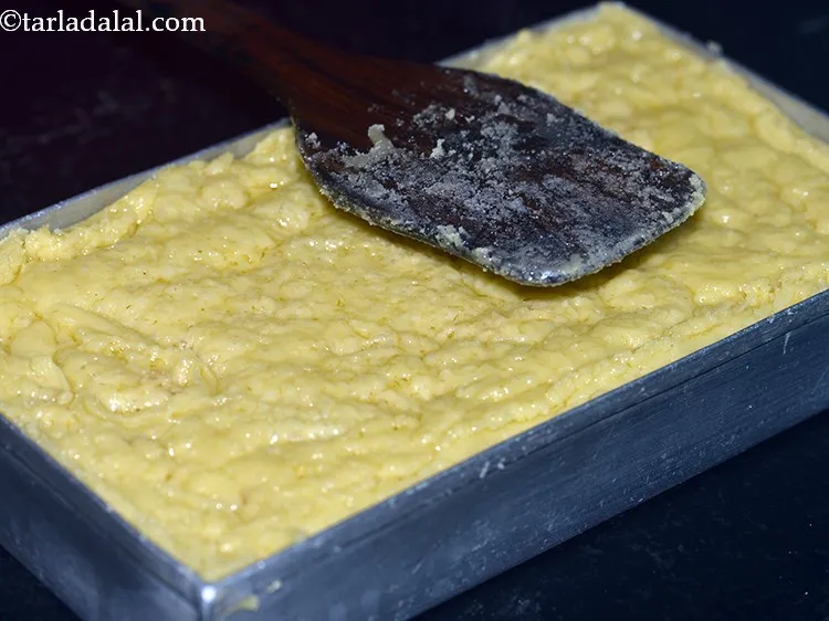 Step 18 – Gently even out the mixture of <strong>Mysore pak</strong> in the tin using the same flat …