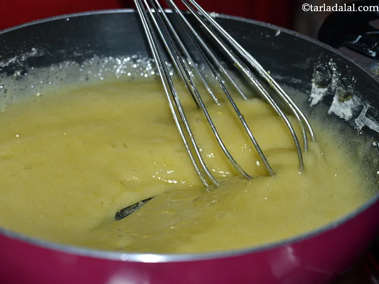Step 12 – Continue mixing well using the whisk until the besan mixes well with the sugar syrup …