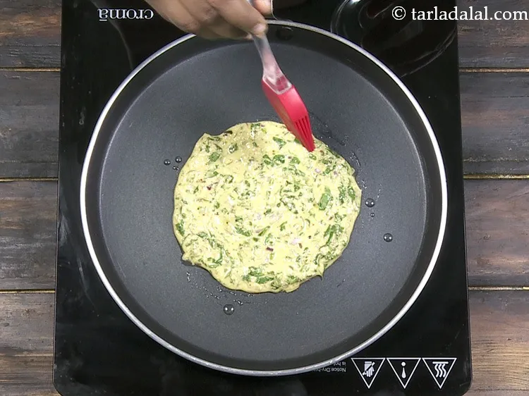 Step 35 – Spread &frac14; tsp of <a href="https://www.tarladalal.com/glossary-oil-671i">oil</a>&nbsp;along the circumference of <strong>oats adai recipe | oats spinach …
