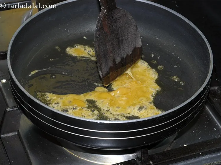 Step 17 – Mix both the ingredients <u><em>( ghee and jaggery) </em></u>and <strong>cook them on a slow flame</strong> …