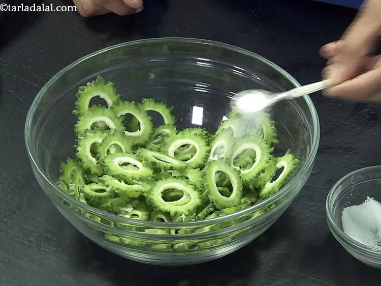 Step 3 – Add a little salt in the deep bowl. The salt extracts the bitterness from karela.