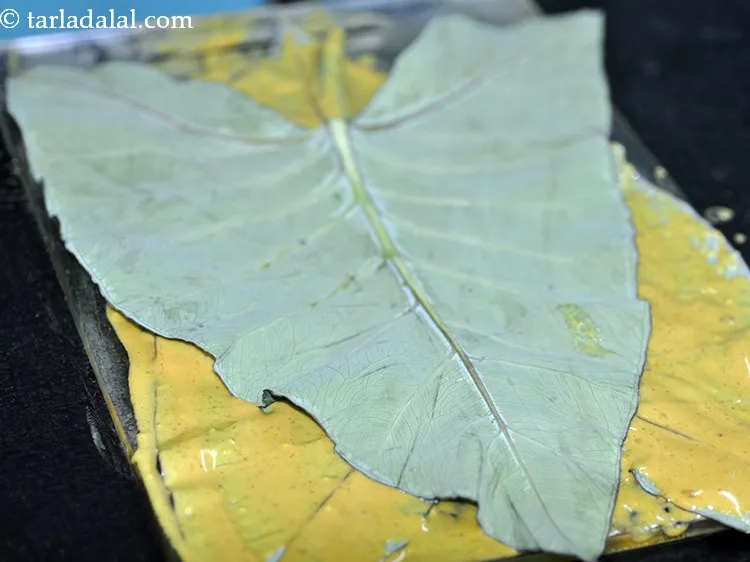 Step 18 – Place another colocassia leaf over it with the light green side again facing upwards and …