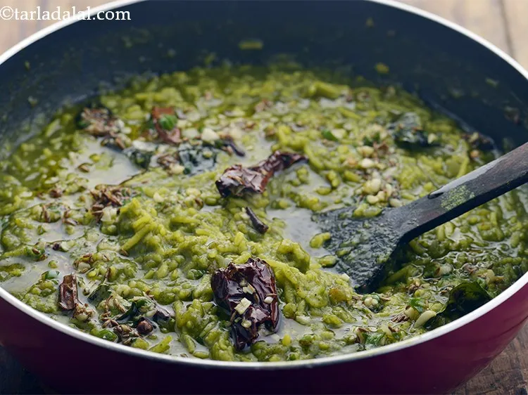 Step 40 – Pour the tempering over the prepared&nbsp;<strong>palak khichdi | palak dal&nbsp;khichdi |</strong>&nbsp;and mix well.
