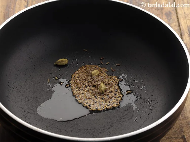स्टेप 12 – तेल गरम होने के बाद, जीरा और इलायची डालें।