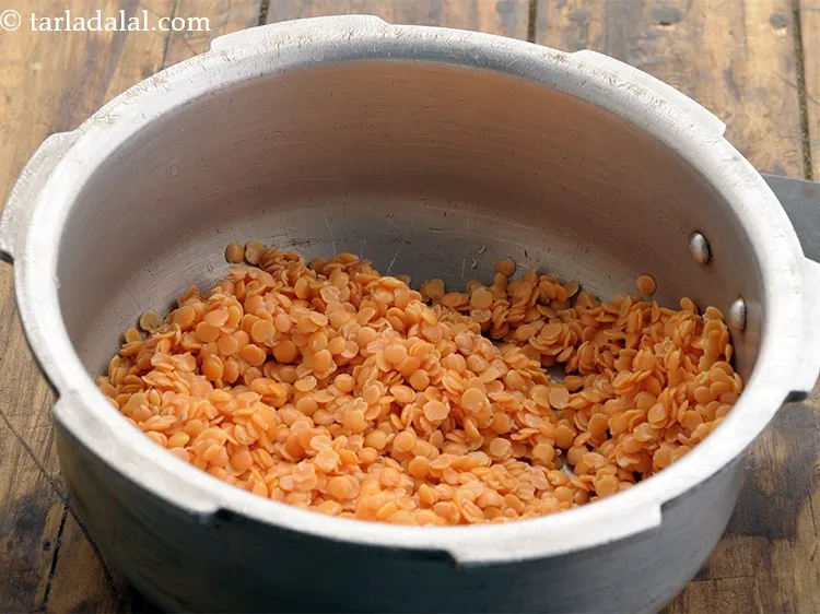 Step 6 – To prepare <strong>healthy palak masoor dal</strong>, in a pressure cooker, add the masoor dal.