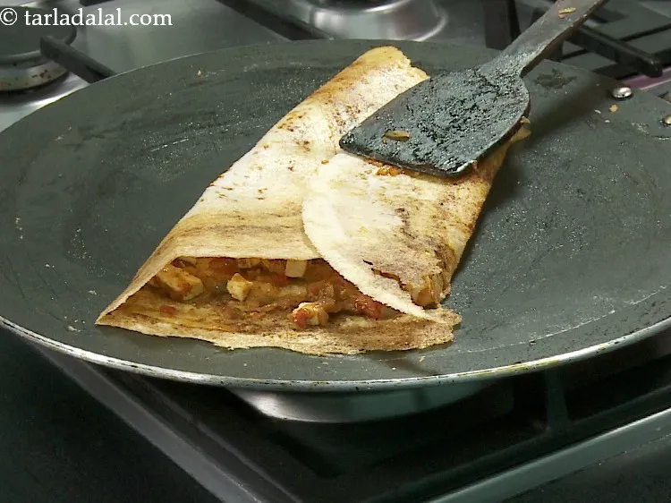 Step 34 – Fold over the <strong>paneer chilli dosa</strong> to make a semi-circle or a roll. It will …