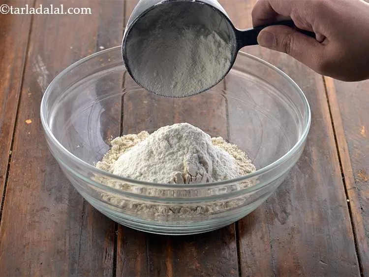 Step 2 – To this, add the plain flour (<em>maida</em>). Adding maida makes the dough more elastic and …