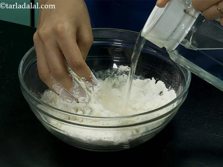 स्टेप 2 – धीरे-धीरे थोड़ा-थोड़ा करके गरम पानी डालें और आटा गूंथना शुरू …