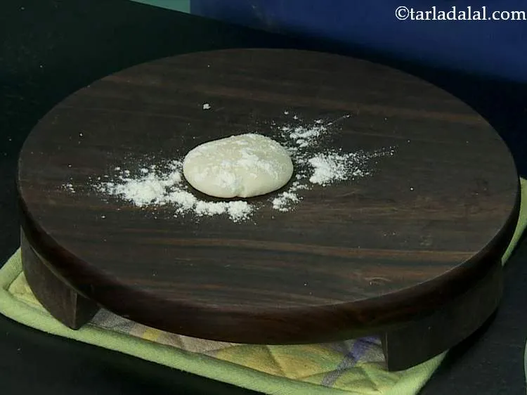 स्टेप 9 – आटे के एक हिस्से को चकले पर फैला लें।
