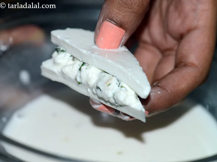 स्टेप 15 – एक स्टफ्ट पनीर त्रिकोण को कॉर्नफ्लोर-पानी के मिश्रण में डुबोकर …