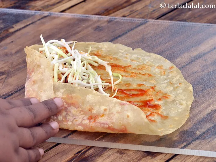 Step 23 – Fold <strong>schezwan paneer roll</strong> from any one side and roll it up tightly.