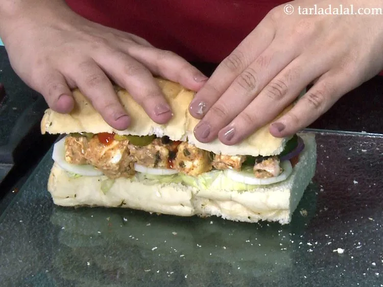 स्टेप 35 – <strong>पनीर टिक्का सब सैंडविच</strong> भारतीय स्नैक को धीरे से दबाएं।