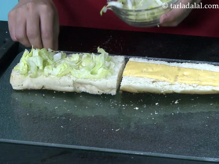 स्टेप 23 – एक ब्रेड के निचले आधे हिस्से पर १/४ कप सलाद …