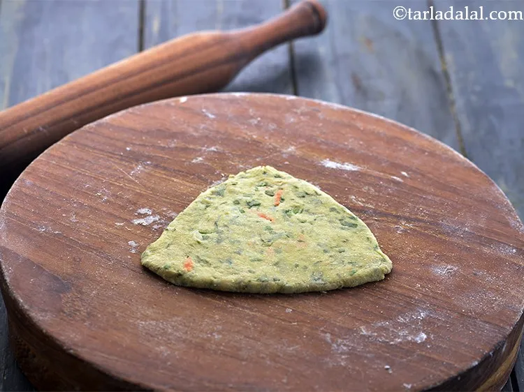 Step 21 – Roll to make a 100 mm. (4&rdquo;) length triangular <strong>paratha</strong> using little flour.