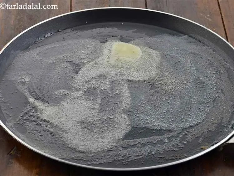 स्टेप 29 – एक बड़ा तवा को गरम करें, २ टीस्पून मक्खन डालें।