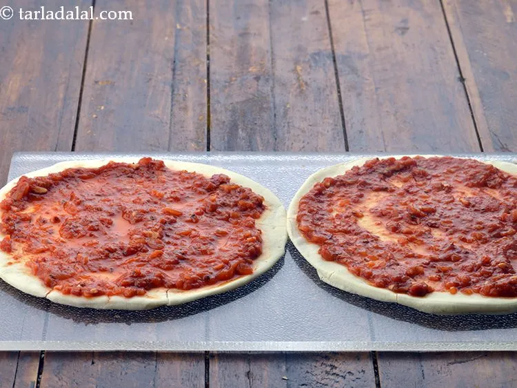 Step 14 – Put 1/4 cup&nbsp;<a href="https://www.tarladalal.com/glossary-pizza-sauce-1889i">pizza sauce</a> on each pizza base and spread it evenly.