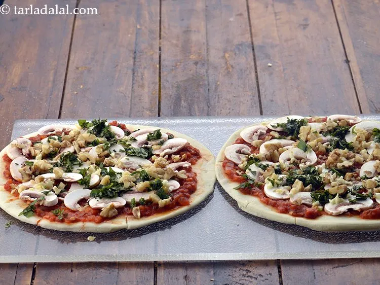 Step 18 – Also spread 1 tbsp&nbsp;<a href="https://www.tarladalal.com/glossary-chopped-basil-804i">chopped fresh basil leaves</a>&nbsp;over each pizza base.