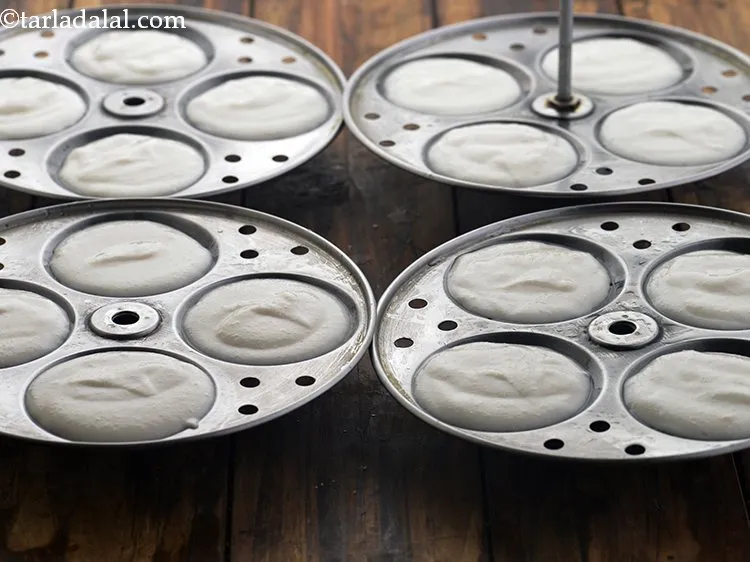 स्टेप 23 – चिकना कीये हुए इडली के सांचों में चम्मच से घोल …