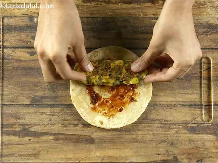 Step 28 – Place a roll on one side of the roti but not at the edge.&nbsp;