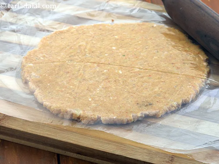 स्टेप 11 – आटे को एक बेलन का उपयोग करके २०० मि। मी। …