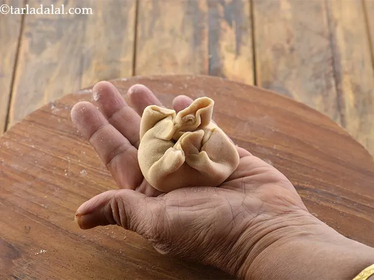 स्टेप 25 – आटे के किनारों को भरवां मिश्रण के ऊपर मोड़ें।