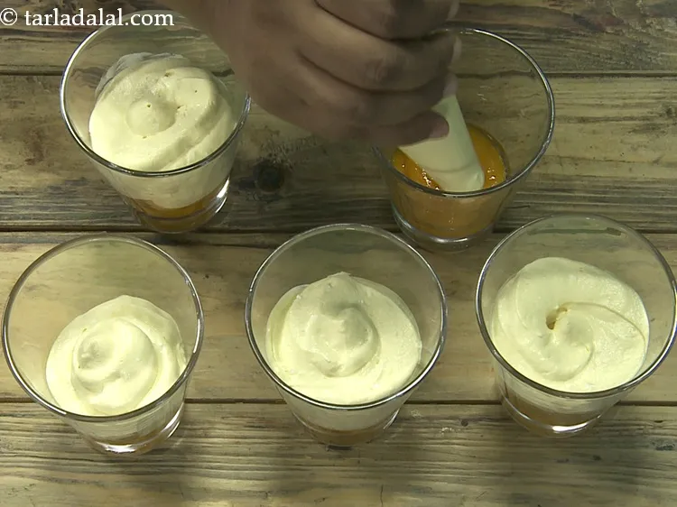 स्टेप 17 – लगभग घुमाएँ. प्रत्येक गिलास में &frac14; कप व्हीप्ड क्रीम-आम का …