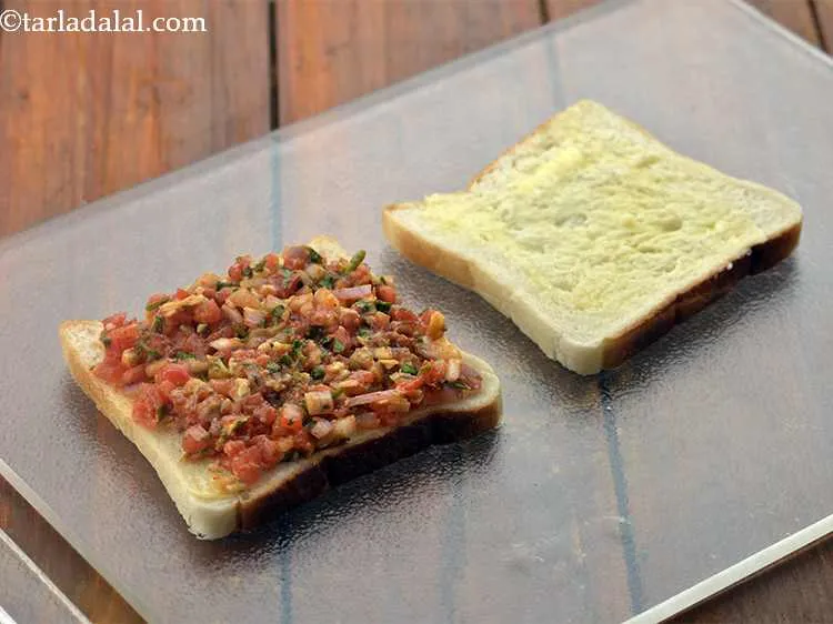 Step 10 – Place a portion of the stuffing on one buttered bread slice and spread it evenly.